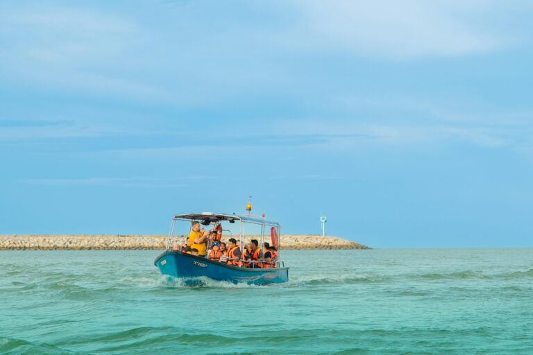 A small motorboat with people wearing life jackets cruising on the sea during summer.