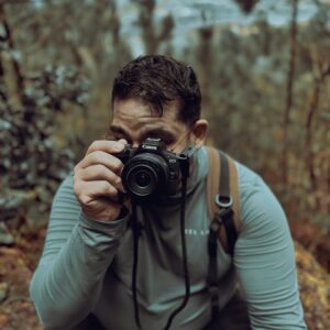 Photographer taking a picture in a lush forest setting.