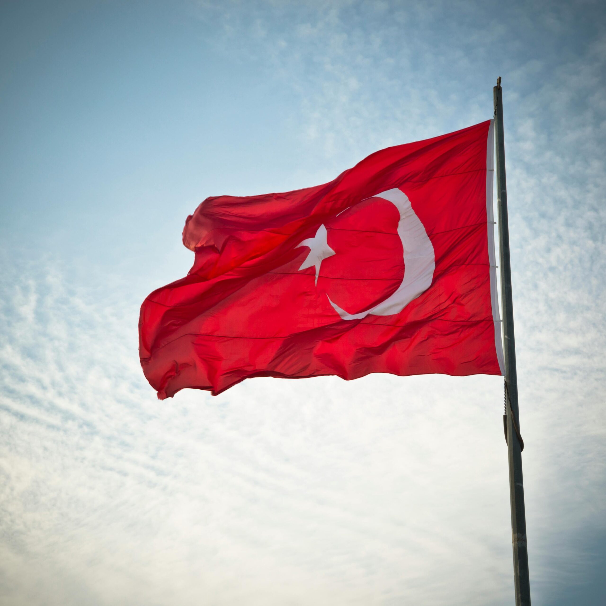 Turkish flag waving prominently against a scenic sky, symbolizing national pride.