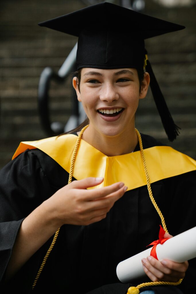 A happy graduate in cap and gown celebrates success with a diploma in hand, symbolizing achievement.